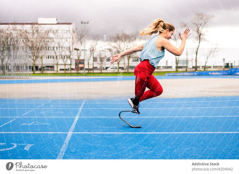 Energetic sportswoman with leg prosthesis running at stadium runner paralympic athlete training energy sprinter female bionic professional racetrack artificial