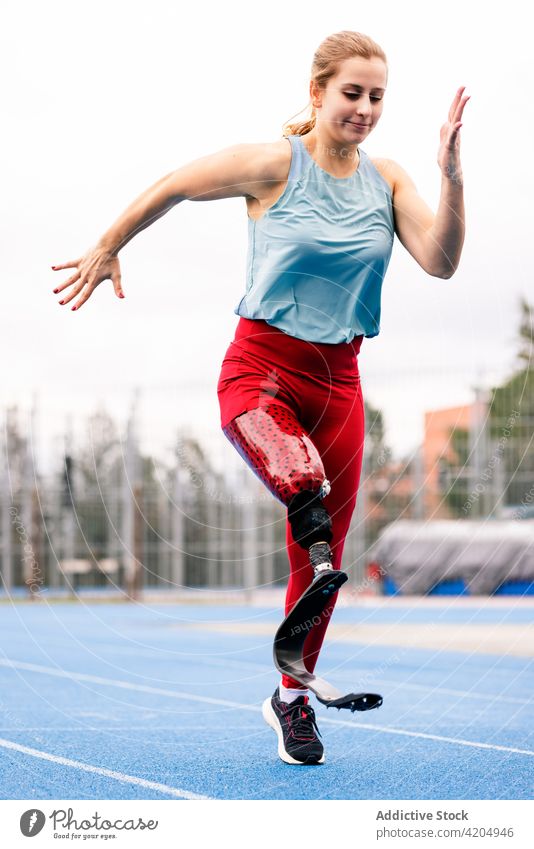 Sportswoman with bionic leg prosthesis at stadium sportswoman run runner paralympic athlete training energy sprinter female professional racetrack artificial