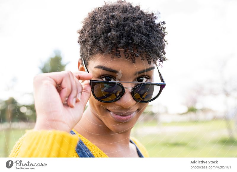 Black woman in stylish sunglasses looking at camera style smile trendy accessory afro charming appearance female ethnic black african american hairstyle park