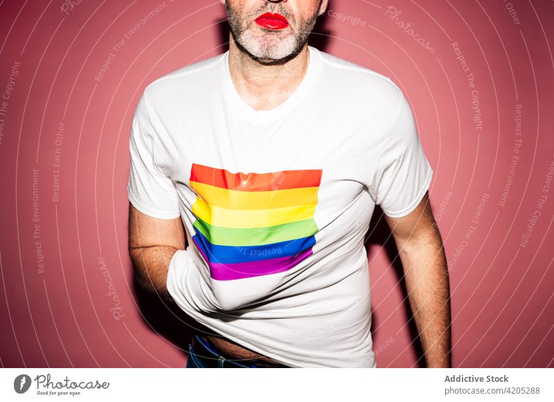 Unrecognizable gay demonstrating t shirt with LGBT flag man cover face lgbt homosexual red lipstick equal tolerance makeup demonstrate concept pride liberty