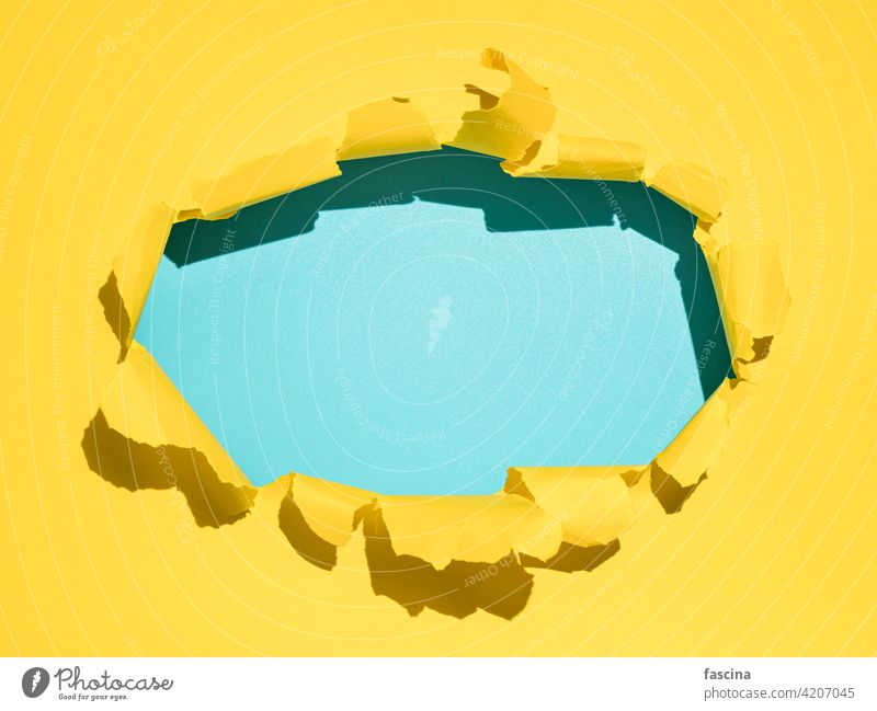 Torn yellow background, copy space paper torn hole rip ripped through sheet page break circle oval open edge wall blue empty blank frame bright background