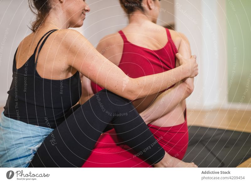 Young slim woman performing Trikonasana yoga pose with support of ethnic  female trainer - a Royalty Free Stock Photo from Photocase