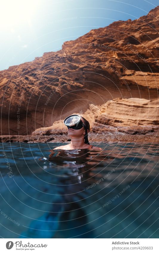 Woman swimming in sea against rocky cliff woman tourist water hobby blue trip vacation female traveler mask clean recreation explore stone nature tourism