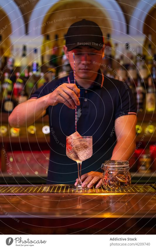 Young Asian bartender stirring a gin tonic cocktail with a spoon in the bar alcohol alcoholic aperitif barista barman beverage bottle business club copy space