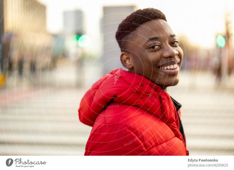 Portrait of a young man standing in a city street, smiling black outside urban millennial African outdoors Warsaw one real people casual lifestyle guy