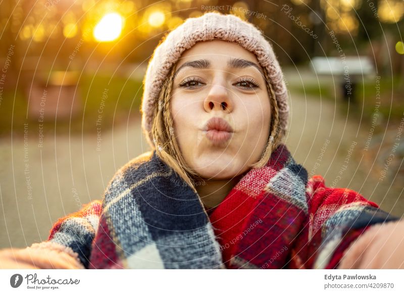 Self portrait of playful young woman outdoors millennial rebel hair braids urban city street teenage trendy cool warm clothes winter style fall one autumn