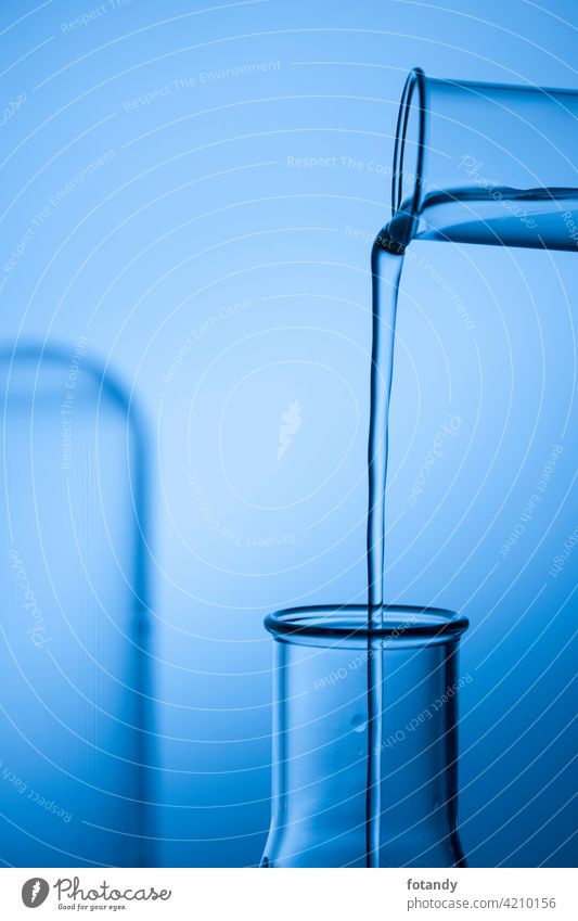 Befüllen eines  Erlmeyer-Kolben aus einem Reagenzglas vor blau getönten Studio-Hintergrund. Analyse befüllen Bewegung Chemie Chemielabor Design Drogen eingießen
