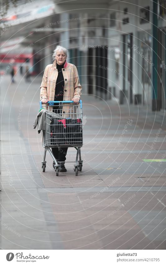 Woman with coat and shopping cart on lonely shopping stroll Coat Human being portrait Exterior shot Adults Loneliness Shopping Trolley Shopping malls