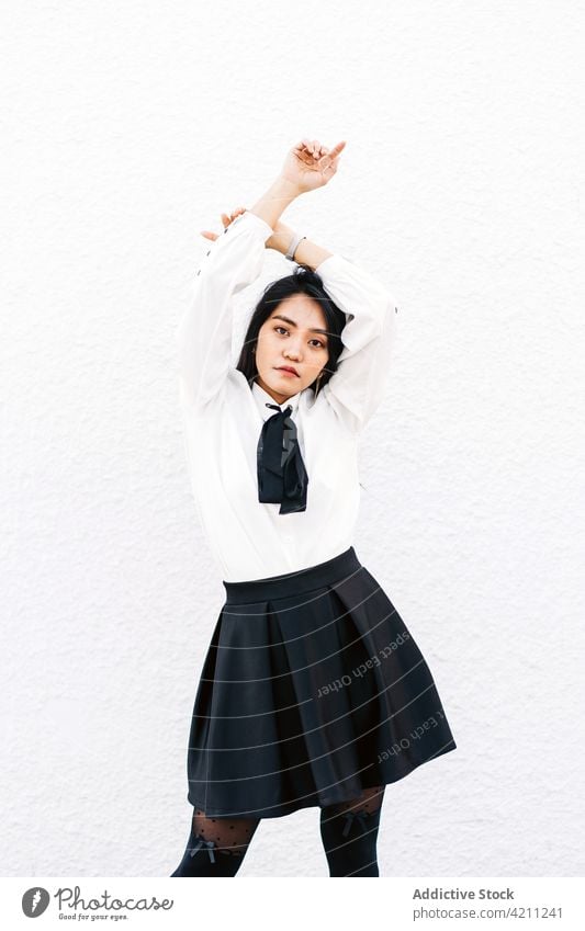 Confident Asian woman with hands crossed above head student uniform cool confident stare individuality posture elegant gaze female arms crossed teen thoughtful