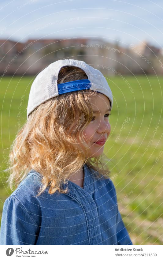 Trendy girl in grassy meadow field summer nature style outfit rest weekend sunny daytime child casual fashion trendy cap freedom season cute childhood kid