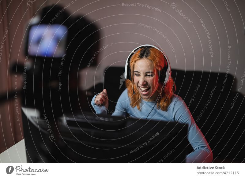 Cheerful female gamer shooting video on camera for blog woman record social media player blogger smile gadget audio professional headphones device headset using