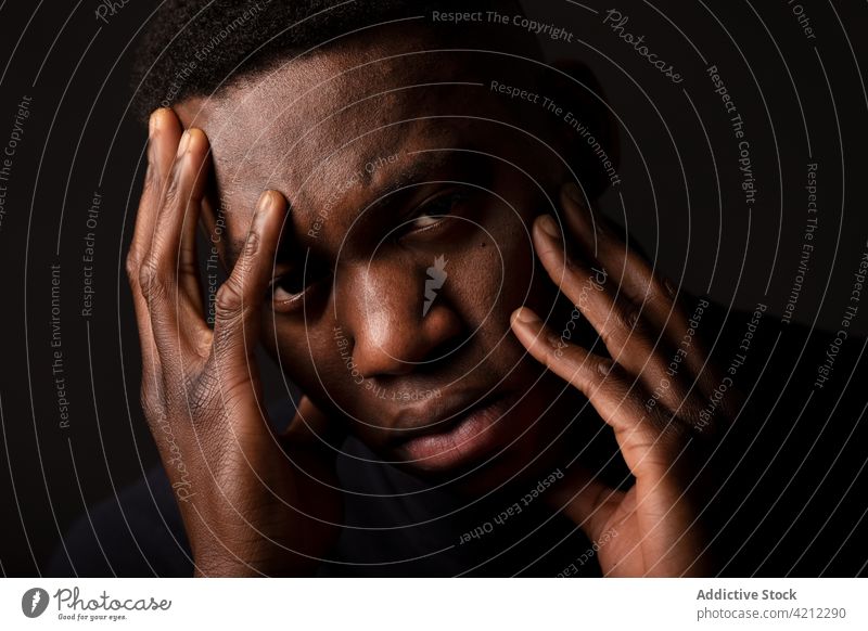 Tired African American guy with hands on face in studio man migraine portrait headache studio shot serious alone thoughtful sad tired african american black