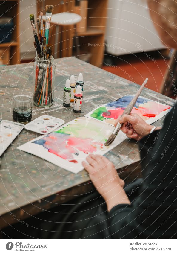 Crop painter creating watercolor abstract picture on paper artist workshop paintbrush creative woman studio female talent artwork palette craftswoman skill