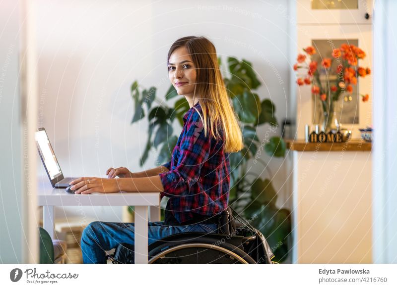 Woman in wheelchair using laptop at home domestic life disability disabled confidence woman independent indoors house people young adult casual female Caucasian