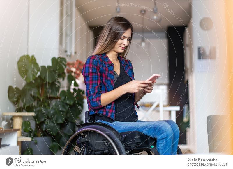 Woman In Wheelchair on Smartphone At Home wheelchair domestic life disability disabled confidence woman independent indoors home house people young adult casual