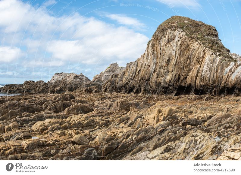Rocky formation on seashore on sunny day rocky beach seascape scenery landscape rough coast stone asturias spain gueirua beach cloudy sky blue sky scenic