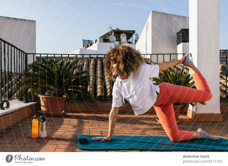 Black woman doing yoga pose on rooftop practice training asana balance relax female ethnic black african american harmony calm mindfulness wellbeing flexible