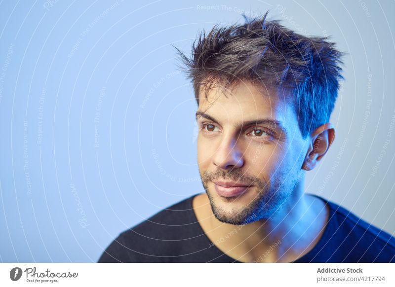 Handsome man in studio with blue neon light style hairstyle haircut trendy handsome appearance male confident illuminate fashion model individuality personality