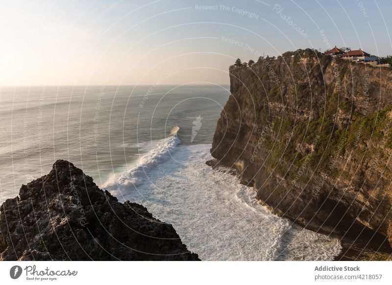 Rocky cliff washed by foamy sea in picturesque nature wavy rocky splash twilight seaside scenic ripple rough seascape ocean water mountain coast idyllic horizon