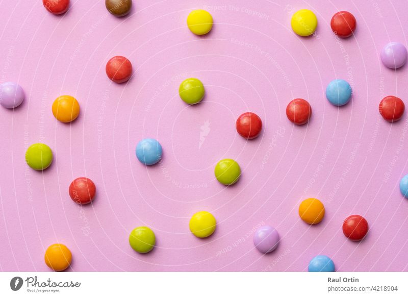 Colorful chocolate candies smarties background.Top view sweets multicolored food texture, on pink background. colorful candy confectionery balls eat bonbons