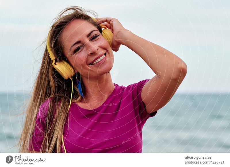 young woman at the beach hearing music with yellow headphones summer beautiful ocean nature girl sea hat relaxation lifestyle female outdoor people sky