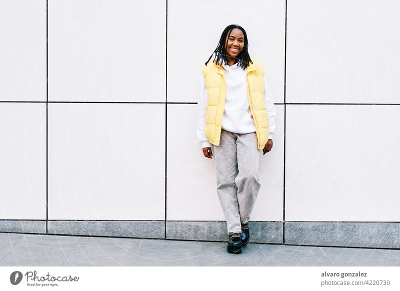 Woman smiling while leaning on street wall. che portrait woman african american urban black outdoors standing style city braids hairstyle clothing afro one