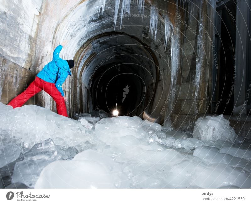 Ice and frost, but light at the end of the tunnel. Man looks into a tunnel in the mountains, frozen thaw water Tunnel Icicle Cold Winter