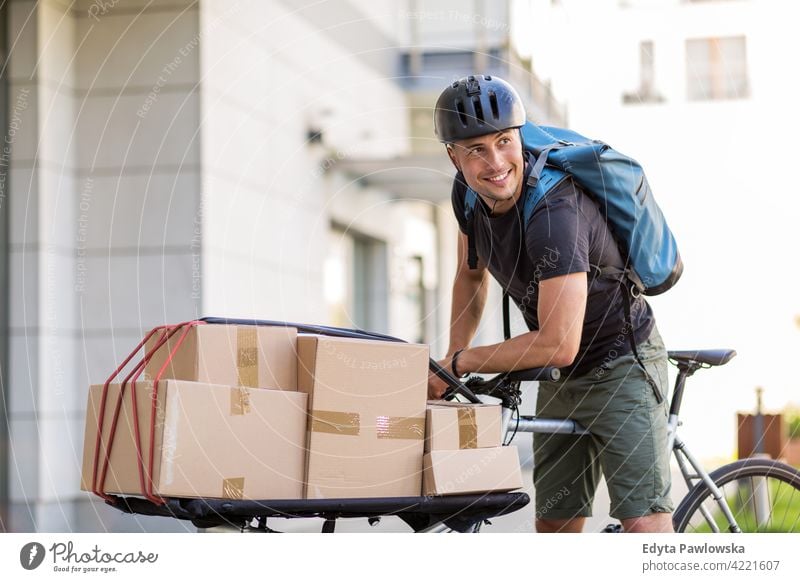 Delivery man with gloves looking away while sitting on bicycle