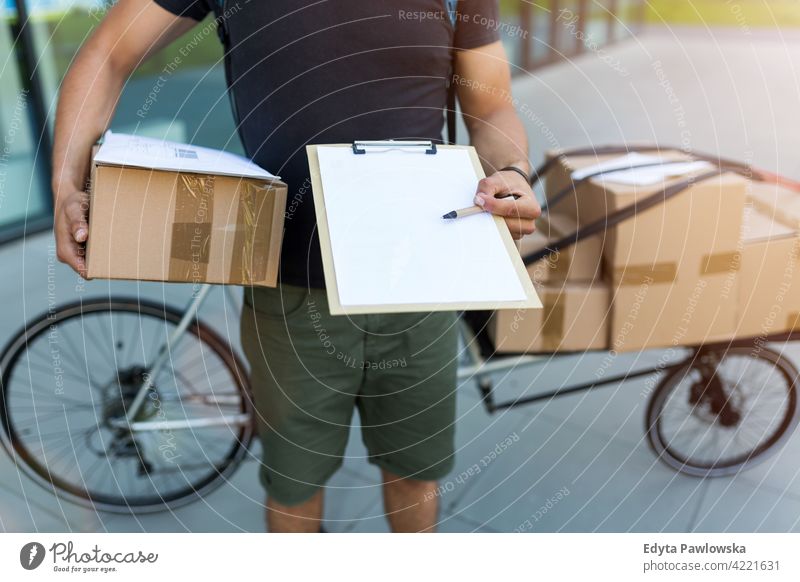 Courier with clipboard and cardboard boxes people young adult man male smiling happy blue collar dispatch rider delivery man delivering package packages parcel