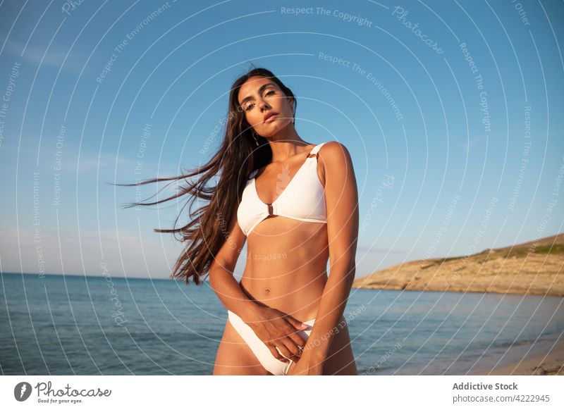 Model in swimsuit on beach against sea model body swimwear feminine confident seascape woman portrait blue sky sandy nature cloudy pretty gentle ocean