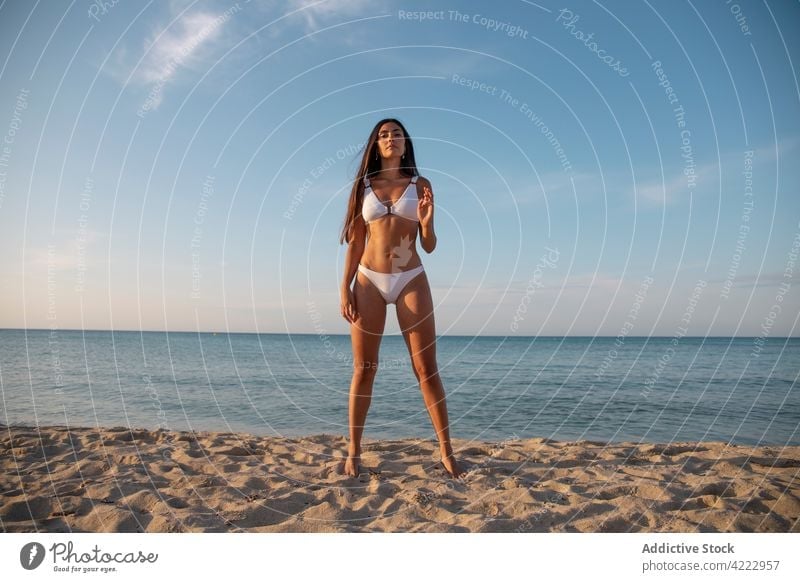 Model in swimsuit on beach against sea model body swimwear feminine confident seascape woman portrait blue sky sandy nature cloudy gentle ocean summer shore