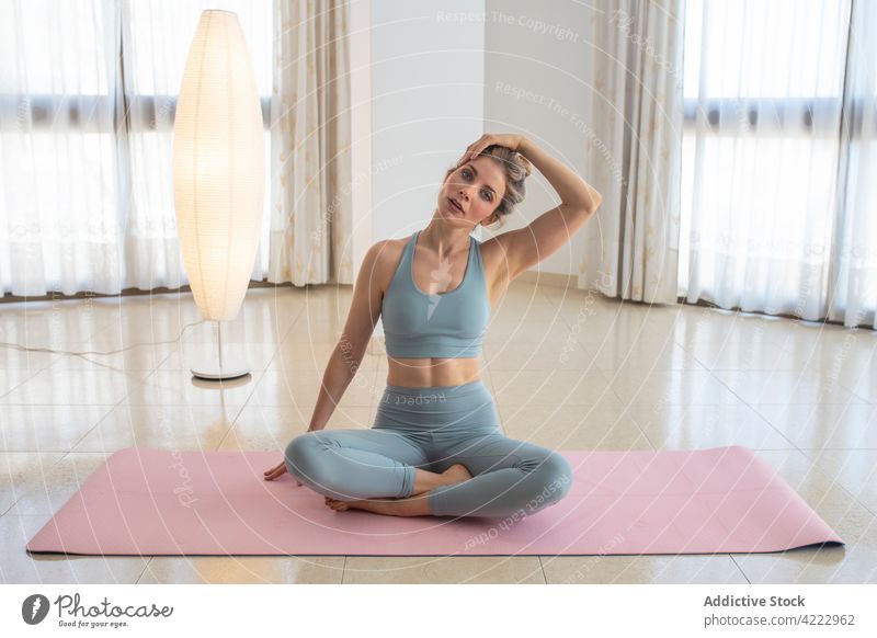 Serene woman warming up body before yoga practice at home stretch neck warm up flexible tranquil relax female healthy wellbeing serene calm sit pose asana