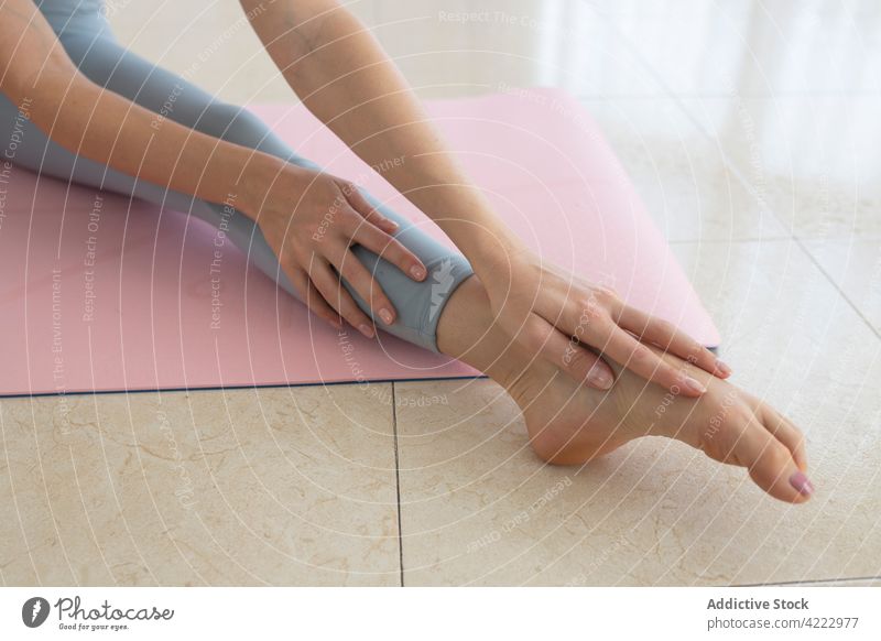 Female touching feet while doing yoga in health club Stock Photo