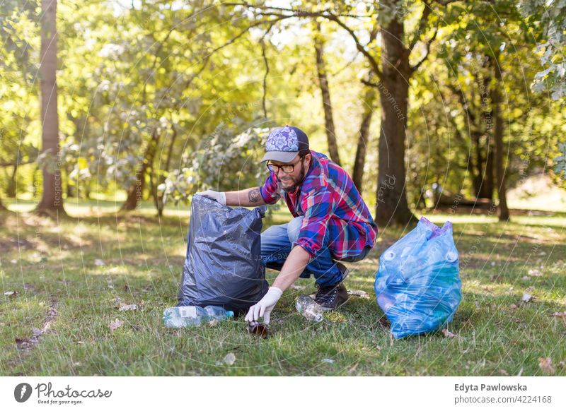 Young man picking up litter in his local park walking hiking forest grass natural countryside environment tree outside male person day outdoors autumn adult