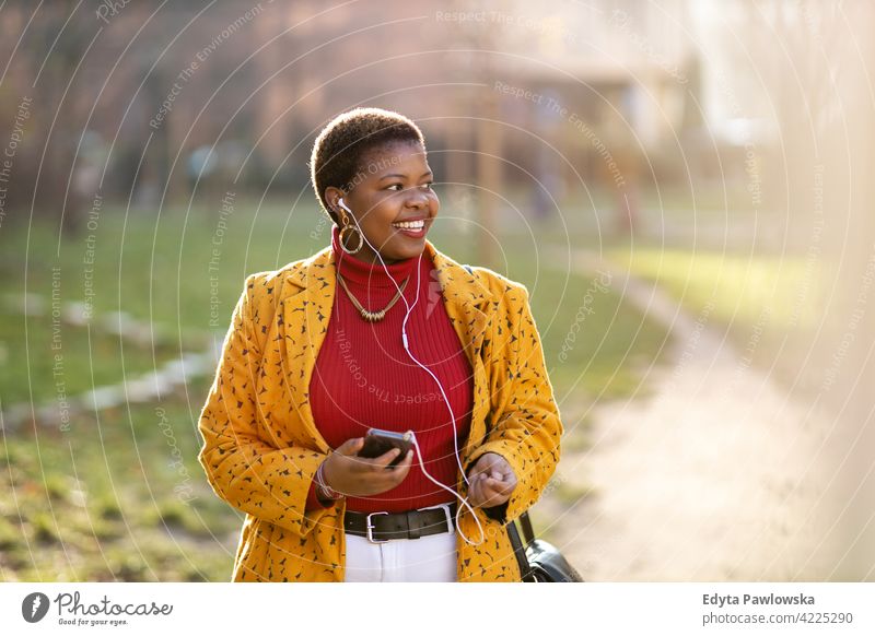 Happy young woman listening music in earphones outdoors day positivity confident carefree people adult casual beautiful attractive female one person smiling