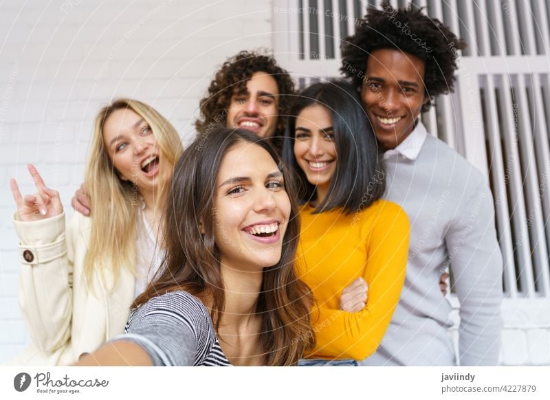 Multi-ethnic group of friends taking a selfie together while having fun outdoors. people smartphone multiracial multi-ethnic caucasian photographing students