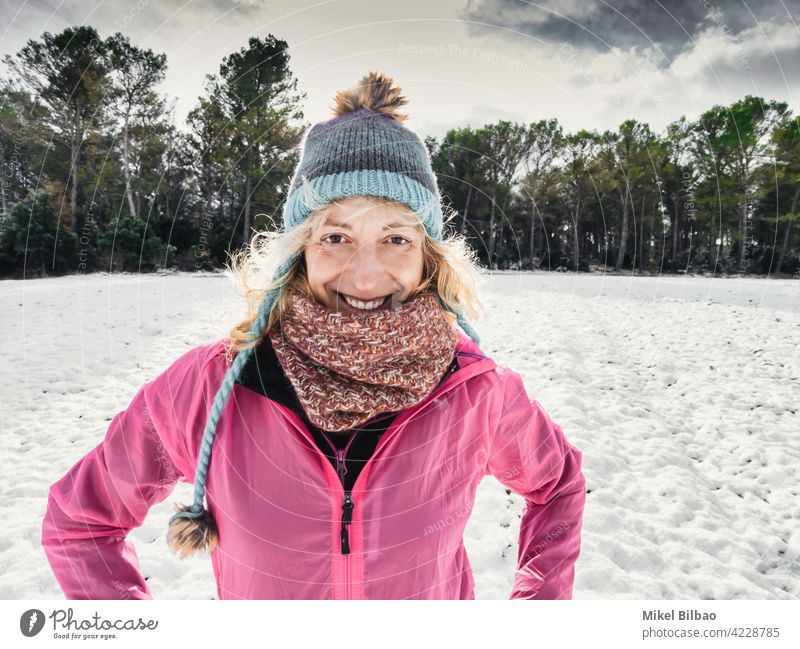 Happy caucasian young woman with a hat and a pink raincoat enjoying snow outdoor in winter time. lifestyle people style of life wanderlust happy having fun