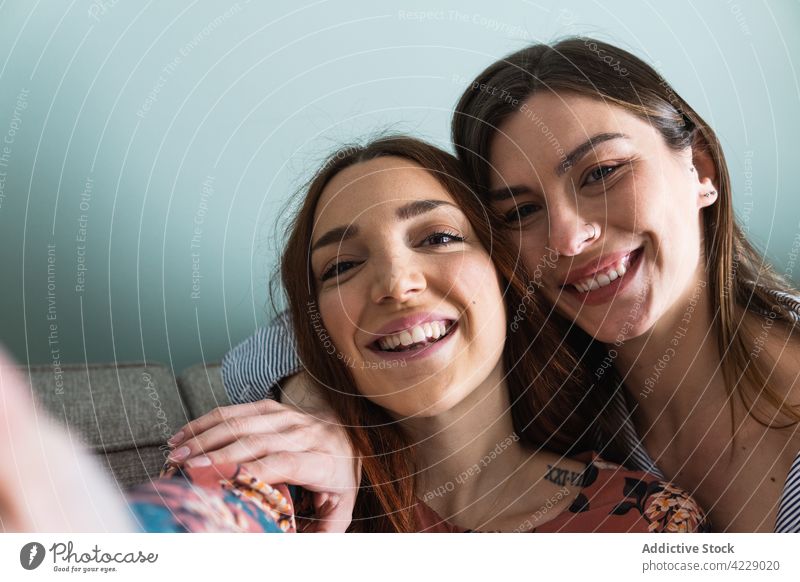 Smiling women hugging and taking selfie on smartphone toothy smile friend happy together embrace self portrait young cheerful girlfriend positive casual