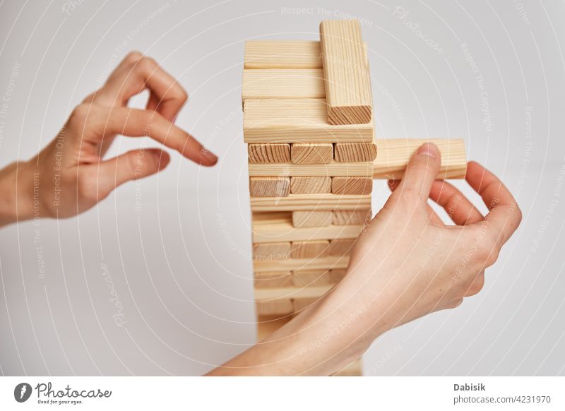 Family play board game. Hands take wooden block from tower. risk brick stack danger concept competition choice build object architecture development structure