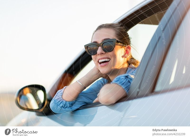 Happy woman wearing sunglasses in a car carsharing confident smiling satisfaction female attractive beautiful young adult joy positive content sitting driver