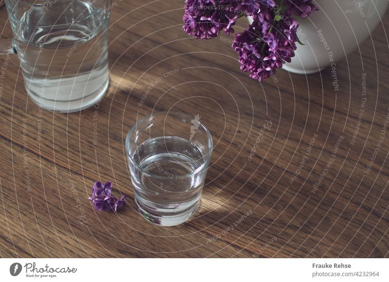 Glass and glass carafe with water on a wooden table with lilac in the vase Tumbler Glass carafe Carafe Water Drinking Thirst Refreshment Healthy Fresh Cold