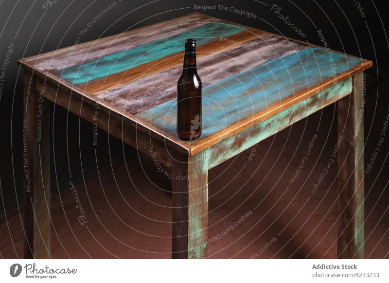 Bottle of beer on old table in house bottle alcohol drink beverage painted natural minimal wooden material glass alcoholic minimalism square shape floor home
