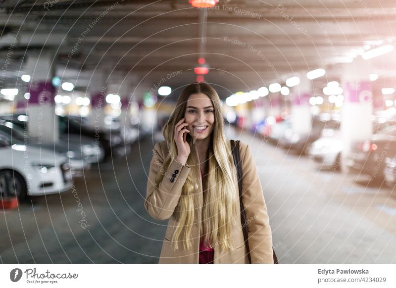 Woman with smart phone in underground parking lot garage car cars vehicle transport transportation enjoying lifestyle young adult people one person casual