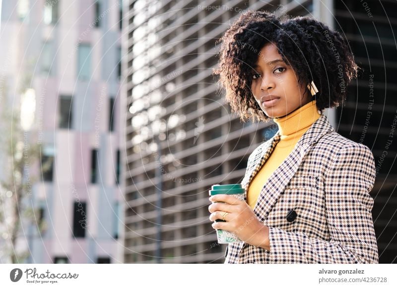 Business woman holding a cup of coffee outdoors. businesswoman afro urban city financial district street entrepreneur portrait professional confident work