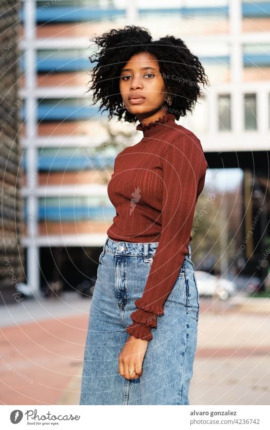 African American woman standing outdoors on the street. young afro black urban portrait fashion city curly hair walking clothes outside background style female
