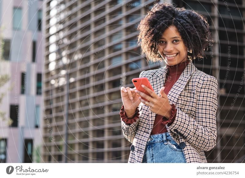 Business woman sending messages on her phone. business afro mobile financial district city urban outdoors professional street connection african american