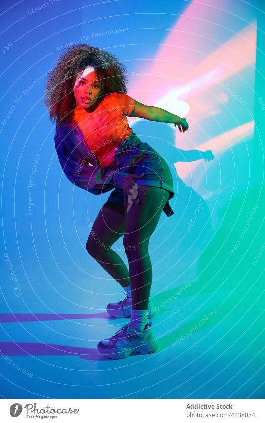 Energetic black woman dancing in dark studio dance perform cool neon dancer move energy skill street style fit vitality active posture dynamic choreography