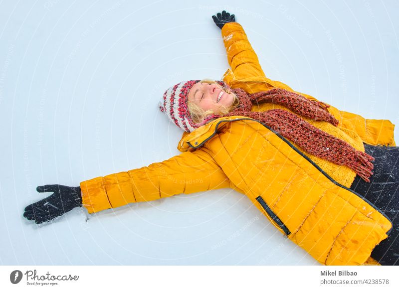 Caucasian young woman enjoying lying in snow outdoor in winter time. lifestyle people style of life lie having fun caucasian female outdoors outside enjoyment