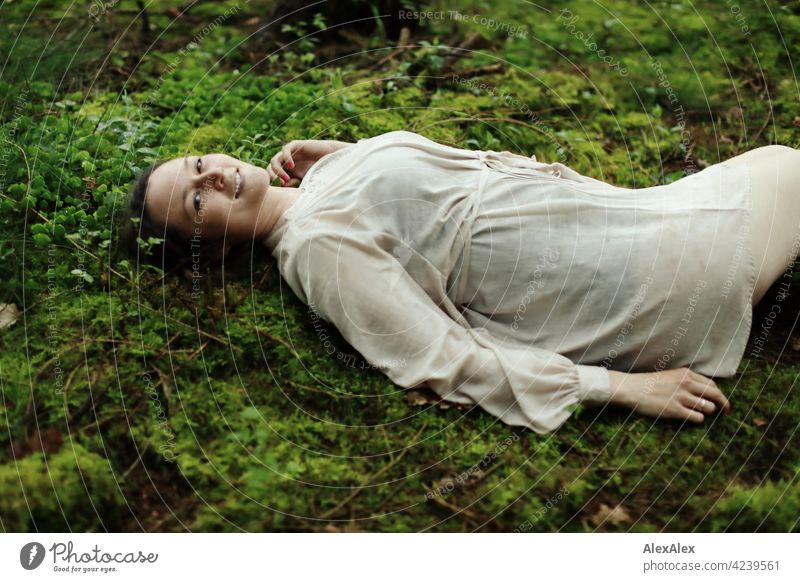 Young woman lying on moss in forest clearing Woman young maiden Moss Forest Ground Woodground pretty daintily Brunette 18 - 30 years 30 - 45 years Long-haired