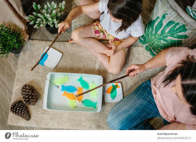Unrecognizable mother and daughter camping at home playing diy fishing game top view unrecognizable family fun at home home vacation fishing pole sister child